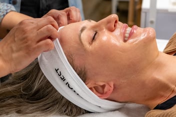 Happy young woman getting a professional treatment with eyes close and smiling and glowing healthy skin