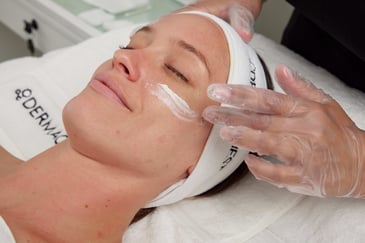Woman getting product applied onto her skin by a licensed skin professional