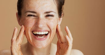woman applying exfoliating scrub onto face